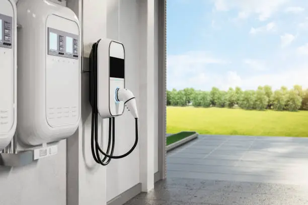 Electrician installing wall-mounted EV charger beside residential garage parking area, Homeowner charging electric vehicle in driveway after new wall-mounted charger installation