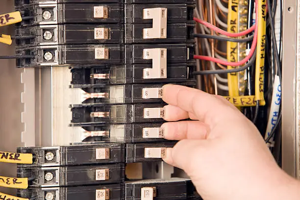 Electrician repairing overheated breaker panel in older Asbury Park home basement