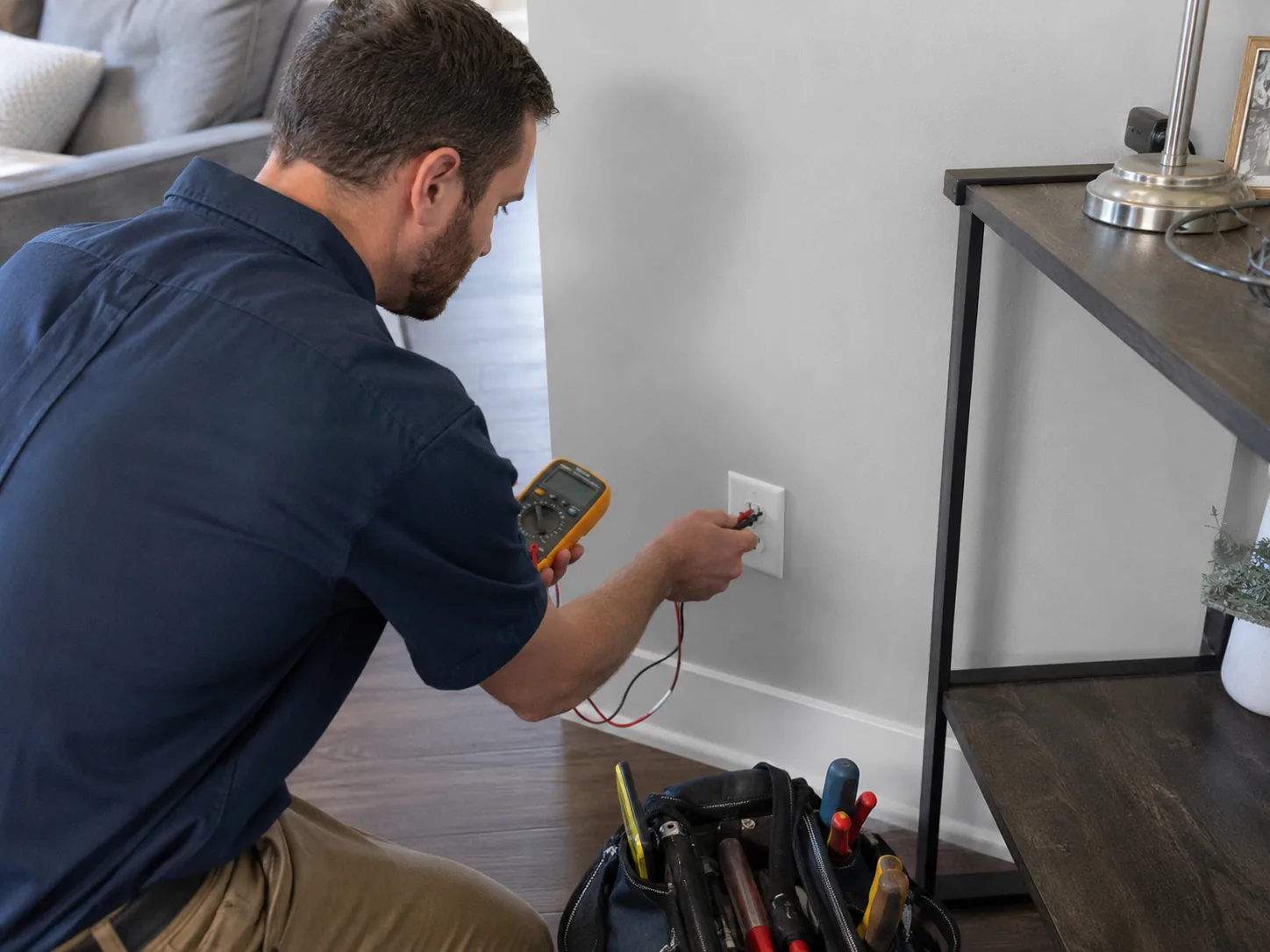Technician performing electrical troubleshooting in a Farmingdale - NJ basement near labeled branch circuits, Electrician performing electrical troubleshooting in Howell Township - NJ while tracing voltage loss at a wall outlet